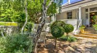 A serene, pebbled garden path leading to the classic Victorian architecture of Parker Cottage, inviting guests to explore its historic beauty and charm.