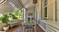 A sun-dappled veranda at Parker Cottage offers a tranquil space for guests to unwind during the afternoon, with comfortable seating and ornamental lanterns adding to the ambiance.