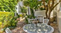 The lush courtyard of Parker Cottage, a haven of serenity with its rich greenery, comfortable white seating, and a sense of peaceful seclusion in the heart of Cape Town.